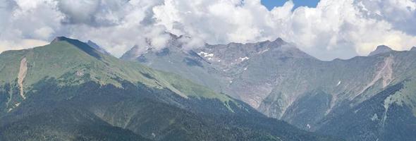 vue sur les montagnes verdoyantes éclairées par la lumière du soleil sur fond de grands nuages blancs. photo