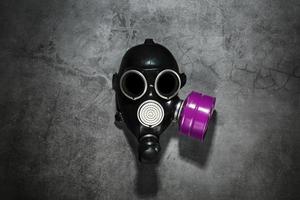 masque à gaz sur fond de pierre noire avec une cartouche filtrante rose. conception post-apocalyptique. photo