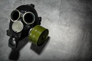 masque à gaz sur fond de pierre noire avec une cartouche filtrante verte. conception post-apocalyptique. photo