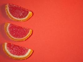 gelée de fruits sous forme de tranches d'orange et de pamplemousse sur fond rouge. photo