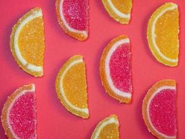 gelée de fruits sous forme de tranches d'orange et de pamplemousse sur fond rouge.bonbons sur la table. photo