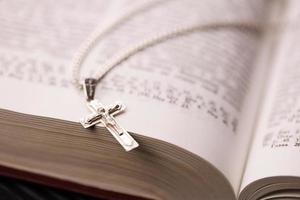 collier en argent avec croix crucifix sur le livre chrétien de la sainte bible sur une table en bois noire. demander des bénédictions à Dieu avec le pouvoir de la sainteté, ce qui porte chance