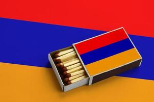 le drapeau arménien est affiché dans une boîte d'allumettes ouverte, qui est remplie d'allumettes et repose sur un grand drapeau photo