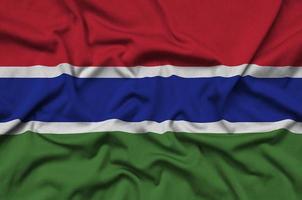 le drapeau de la gambie est représenté sur un tissu de sport avec de nombreux plis. bannière de l'équipe sportive photo
