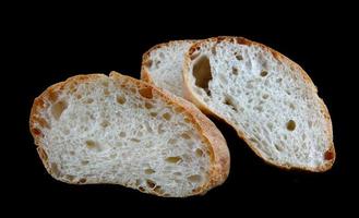 ciabatta, une miche de pain coupée en deux isolée sur fond noir. photo