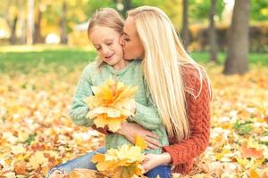 femme et fille tenant des feuilles jaunes d'automne photo