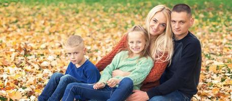 portrait de jeune famille assise dans les feuilles d'automne photo