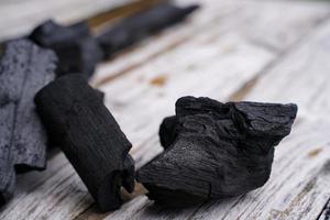 charbon de bois noir sur fond de vieux bois, le charbon de bois est indispensable dans les grillades. photo