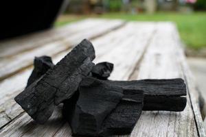 charbon de bois noir sur fond de vieux bois, le charbon de bois est indispensable dans les grillades. photo