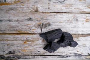 charbon de bois noir sur fond de vieux bois, le charbon de bois est indispensable dans les grillades. photo
