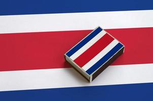 le drapeau du costa rica est représenté sur une boîte d'allumettes posée sur un grand drapeau photo