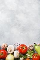 ensemble de différents légumes de saison sur un fond de béton gris. tomate courgette oignon ail champignons persil épices. espace de copie de cadre. photo
