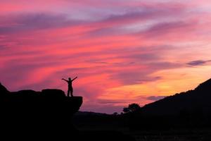 silhouette d'un homme sur le rocher au coucher du soleil photo