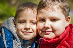 deux frères dans la forêt au printemps. interactions des enfants. promenez-vous dans le parc verdoyant à l'air frais. la lumière magique des rayons du soleil tombe derrière. photo