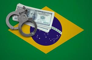 drapeau du brésil avec des menottes et un paquet de dollars. le concept d'enfreindre la loi et les crimes de voleurs photo