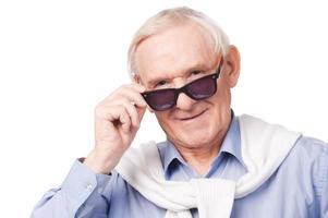 grand-père à la mode. homme âgé élégant portant des lunettes de soleil et regardant la caméra en se tenant debout sur fond blanc photo