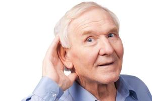 qu'avez-vous dit bel homme senior tenant la main près de son oreille et souriant en se tenant debout sur fond blanc photo