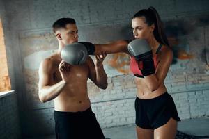 Monter une jeune femme pratiquant le poinçonnage pendant que son entraîneur de boxe lui enseigne photo