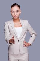 bienvenue à bord confiante jeune femme d'affaires tendant la main pour serrer en se tenant debout sur fond gris photo