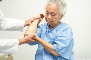 Une patiente asiatique âgée ou âgée d'une vieille dame ressent de la douleur au coude sur son lit dans une salle d'hôpital de soins infirmiers, concept médical solide et sain. photo