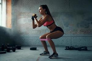 belle jeune femme utilisant une bande de résistance élastique tout en faisant de l'exercice dans une salle de sport photo