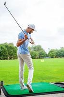 coup de départ. Vue arrière sur toute la longueur du jeune golfeur jouant au golf photo