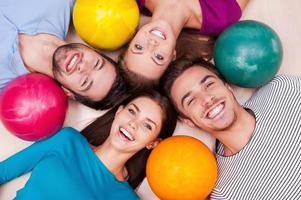 l'amitié est toujours gagnante dans nos jeux. amis joyeux allongés et près de leurs boules de bowling et regardant la caméra photo