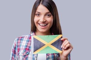 il n'y a pas de frontières pour l'amitié. heureux, jeunes femmes, drapeau, de, jamaïque, quoique, debout, contre, arrière-plan gris photo