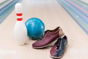 matériel de boules. gros plan sur des chaussures de bowling, une boule bleue et une broche allongée sur une piste de bowling photo
