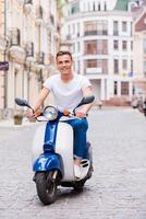 juste rouler. beau jeune homme à lunettes de soleil faisant du scooter le long de la rue et souriant photo