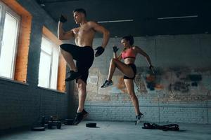 couple en forme confiant sautant tout en faisant de l'entraînement croisé dans la salle de sport ensemble photo