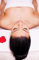 sérénité du spa. vue de dessus d'une belle jeune femme enveloppée dans une serviette allongée sur une table de massage et gardant les yeux fermés photo