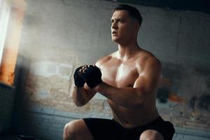 jeune homme confiant debout en position accroupie pendant l'entraînement en salle de sport photo