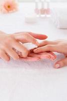 appliquer un antiseptique sur les ongles. gros plan sur un maître de manucure pulvérisant un antiseptique sur un doigt féminin photo