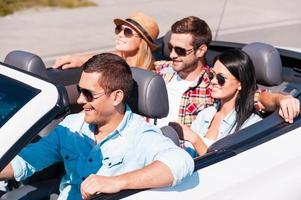 voyage amusant. vue de dessus de jeunes gens heureux profitant d'un voyage sur la route dans leur cabriolet blanc photo