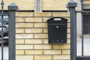 boîte aux lettres d'une maison privée, une boîte aux lettres en métal noir installée sur une clôture en brique d'une maison d'habitation privée photo