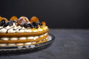 délicieux gros gâteau à la crème rond et frais décoré de pruneaux, d'abricots secs et de chocolat photo