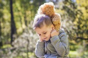 un garçon mignon joue avec un ourson dans la forêt. les rayons du soleil enveloppent l'espace de la clairière d'une souche. une histoire magique d'interactions pour le livre. espace pour la copie. sélectif photo