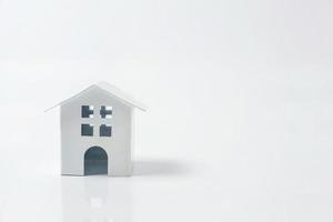 concevoir simplement avec une maison de jouet blanche miniature isolée sur fond blanc. concept de maison de rêve d'assurance de propriété hypothécaire. espace de copie. photo
