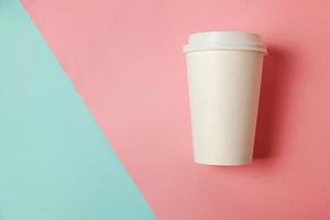 tasse à café en papier design simplement plat sur fond bleu rose pastel coloré à la mode. contenant de boisson à emporter. bonjour réveillez-vous concept éveillé. modèle de maquette de boisson. espace de copie vue de dessus. photo