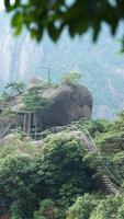 les beaux paysages de montagnes avec la forêt verte et une route en planches construite le long d'une falaise dans la campagne de la chine photo