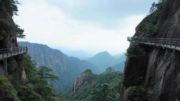 les beaux paysages de montagnes avec la forêt verte et une route en planches construite le long d'une falaise dans la campagne de la chine photo