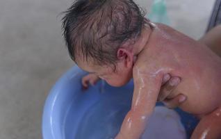 mignon petit garçon baigné par sa mère les enfants sont heureux dans la salle de bain. photo