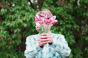 un gars tient un bouquet de tulipes en les tenant devant lui photo