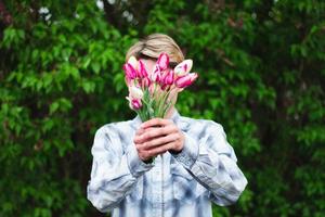 un gars tient un bouquet de tulipes en les tenant devant lui photo