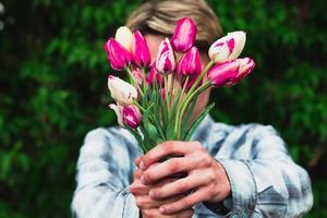 un gars tient un bouquet de tulipes en les tenant devant lui photo