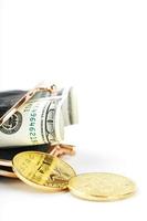 un portefeuille noir ouvert avec de l'argent, des dollars et des pièces de monnaie bitcoin sur fond blanc. photo