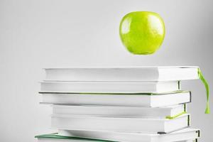 vert pomme suspendu au-dessus des livres isoler sur un fond blanc. photo