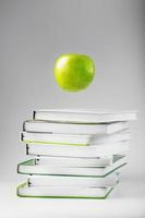 une pomme verte plane au-dessus d'isoler des livres sur un fond blanc. photo