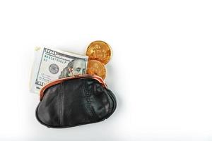 un portefeuille noir ouvert avec de l'argent, des dollars et des pièces de monnaie bitcoin sur fond blanc. photo